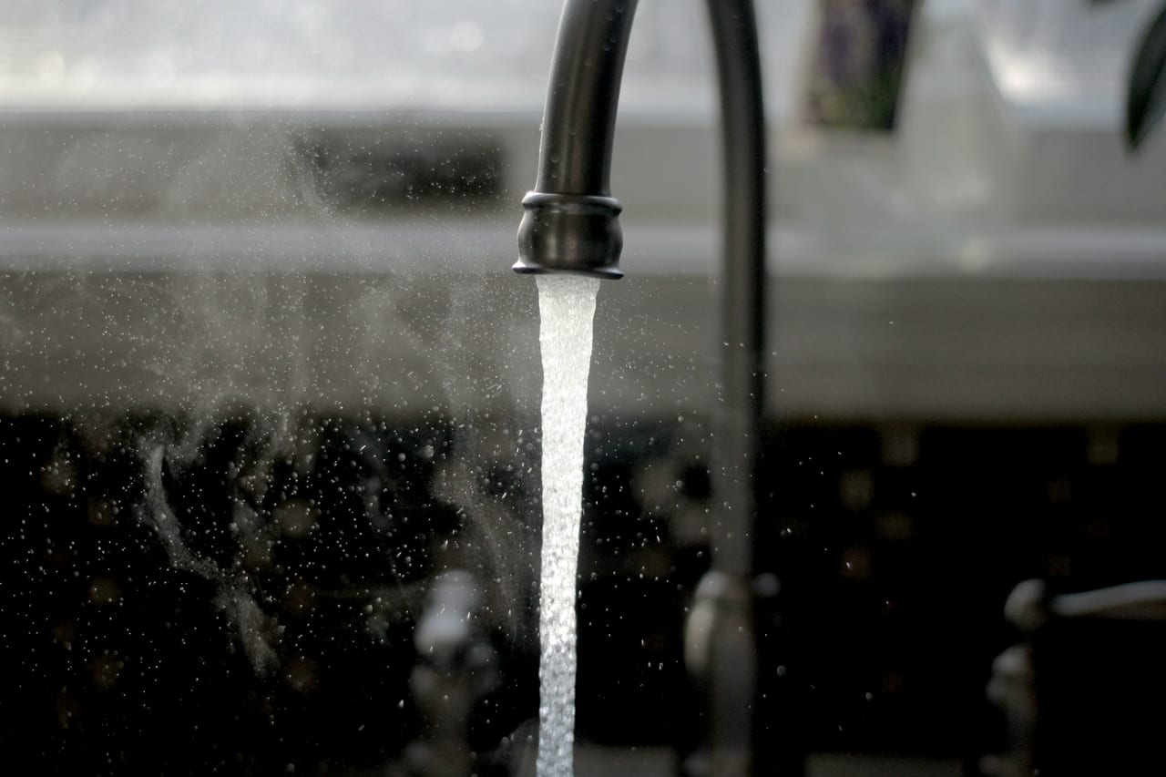 Water flowing from a kitchen tap into a stainless sink